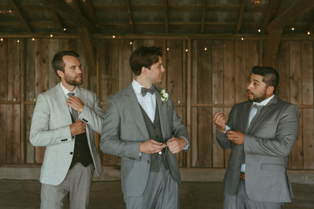 groom getting ready in the cocktail barn with groomsmen