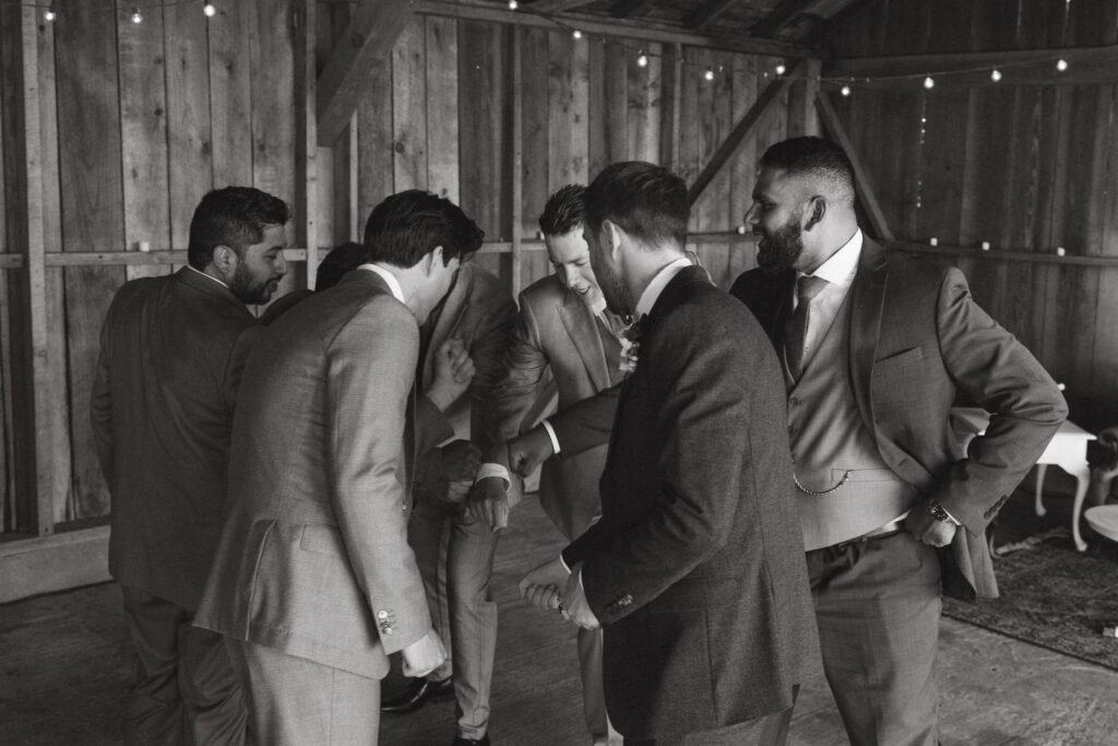 groom getting ready in the cocktail barn with groomsmen