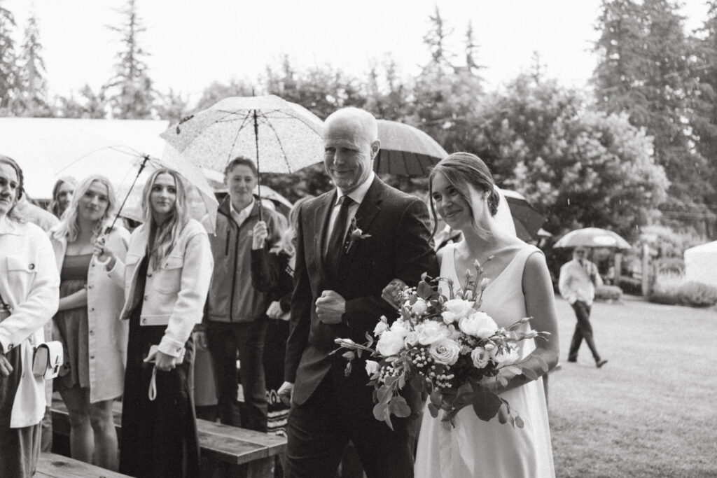 bride's father walking her down the aisle on a rainy day