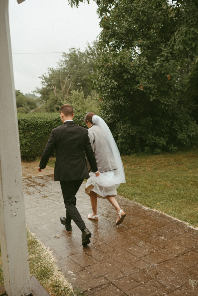 bride and groom running off together in the rain 