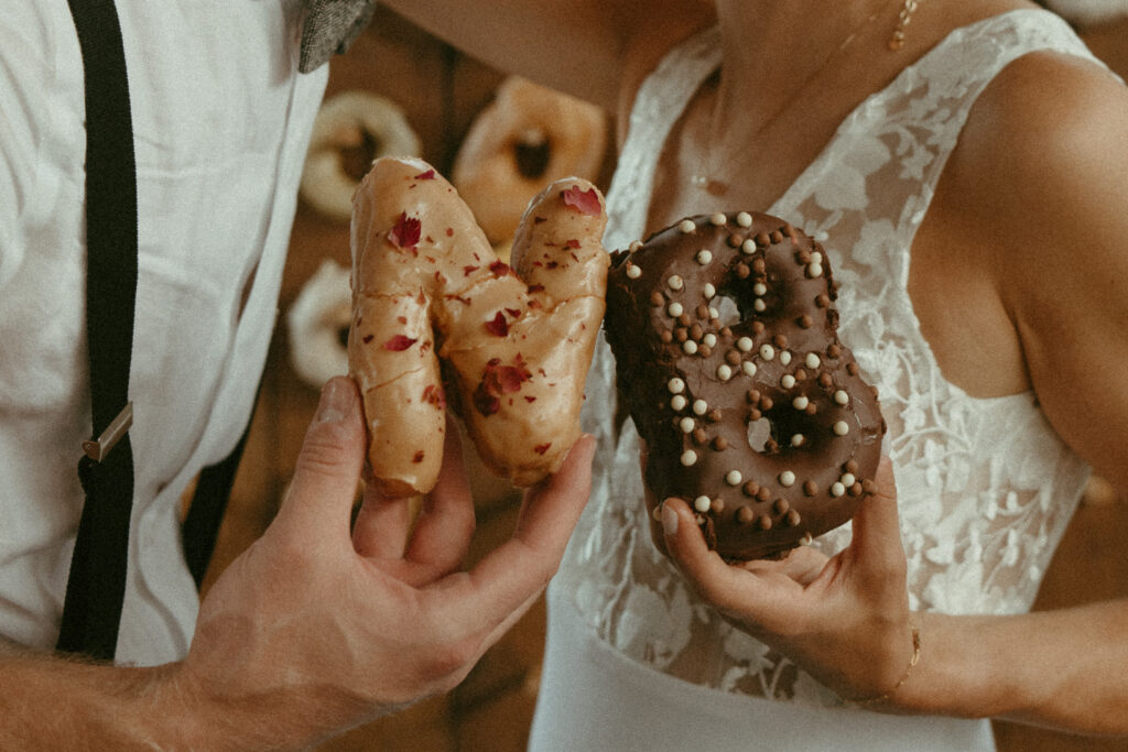 bride and groom share donuts 