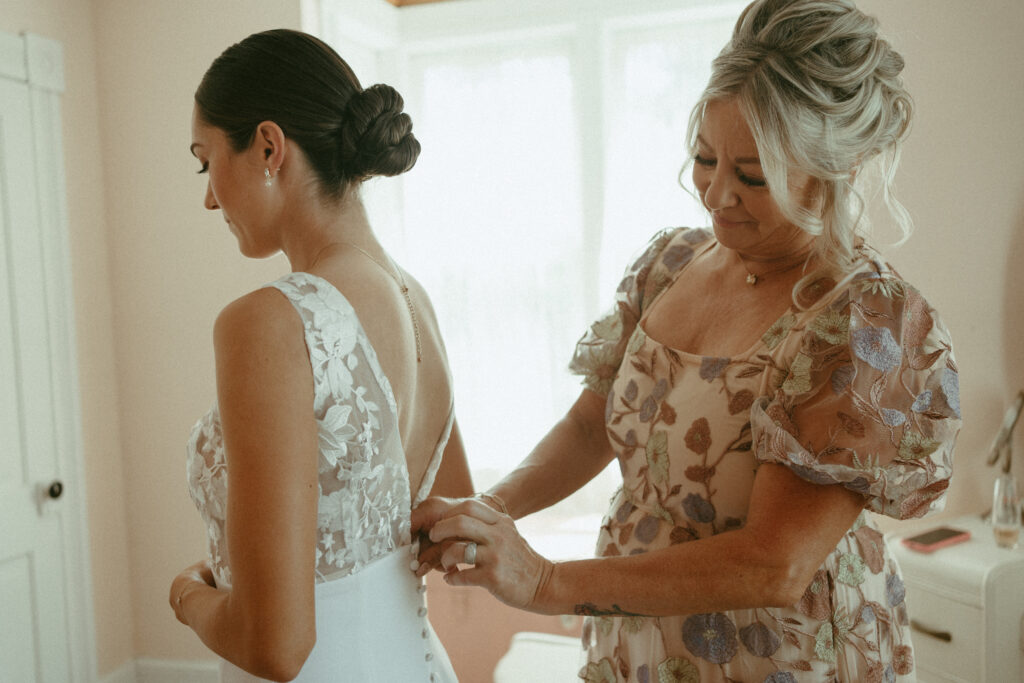 bride's mom doing up her dress 