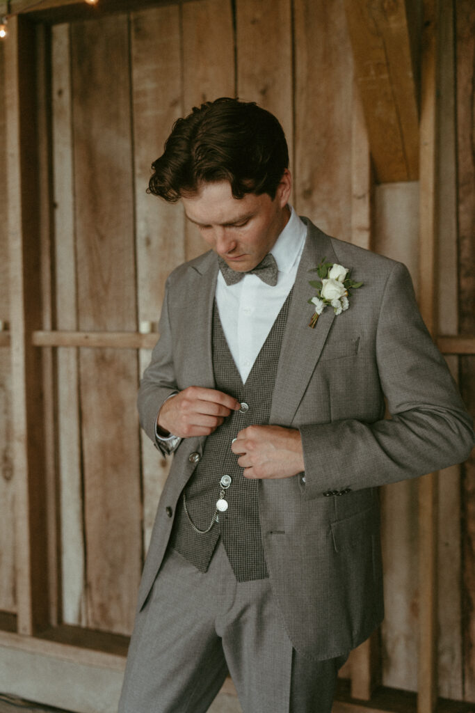 groom doing up vest buttons